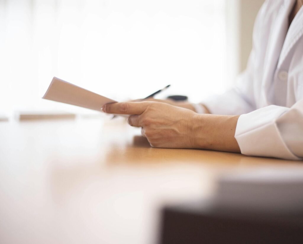 Close-up of a doctor in a lab coat reviewing paperwork at a desk.
